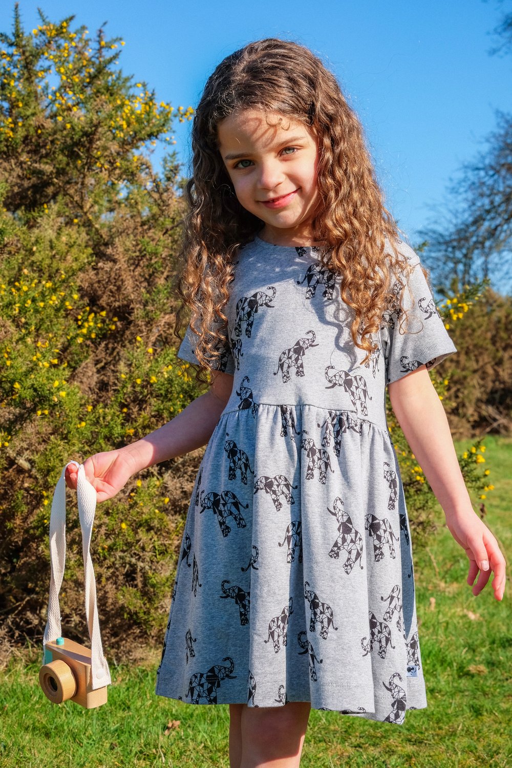 Girl wearing organic grey elephant dress in a garden