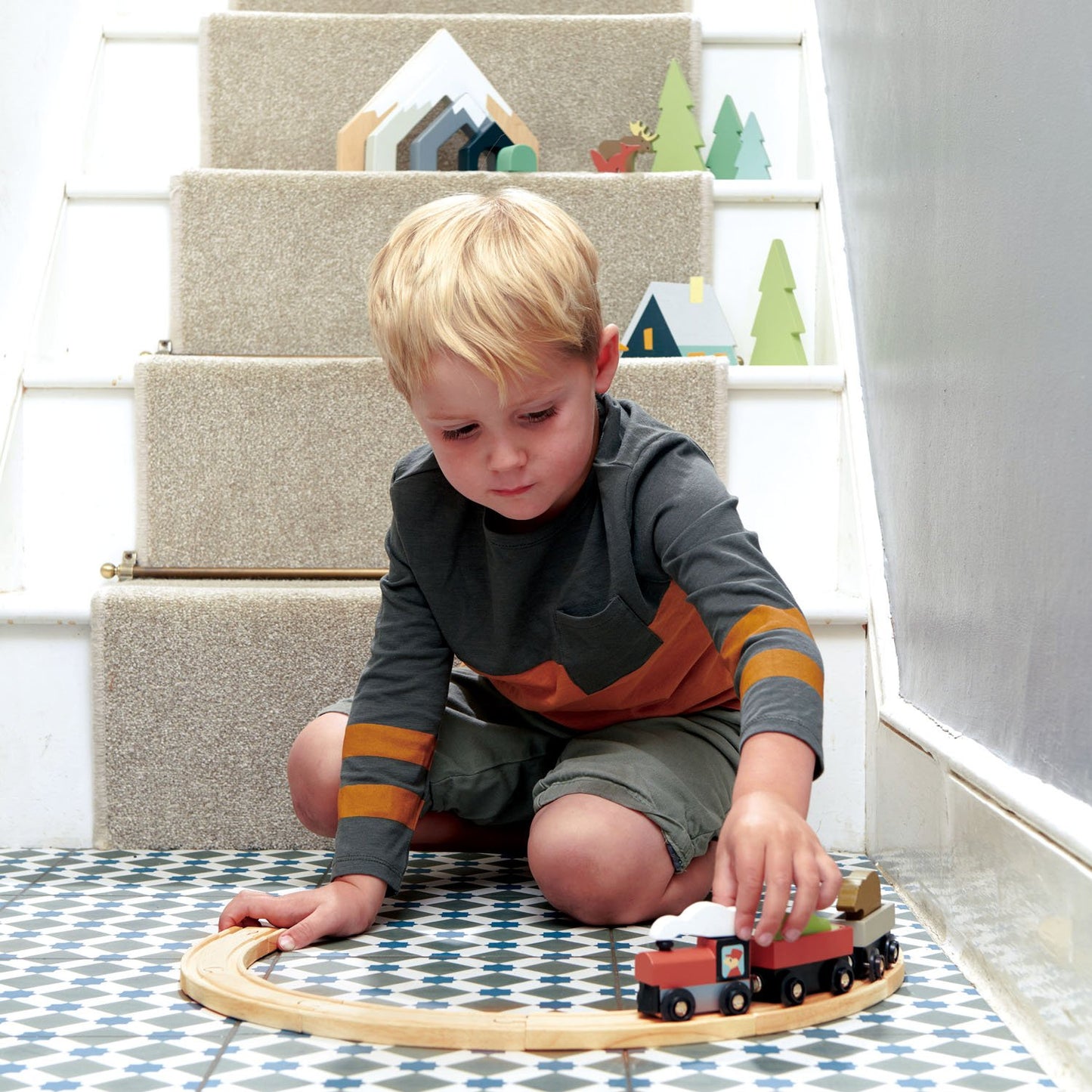 Boy having fun with wooden treetops train set
