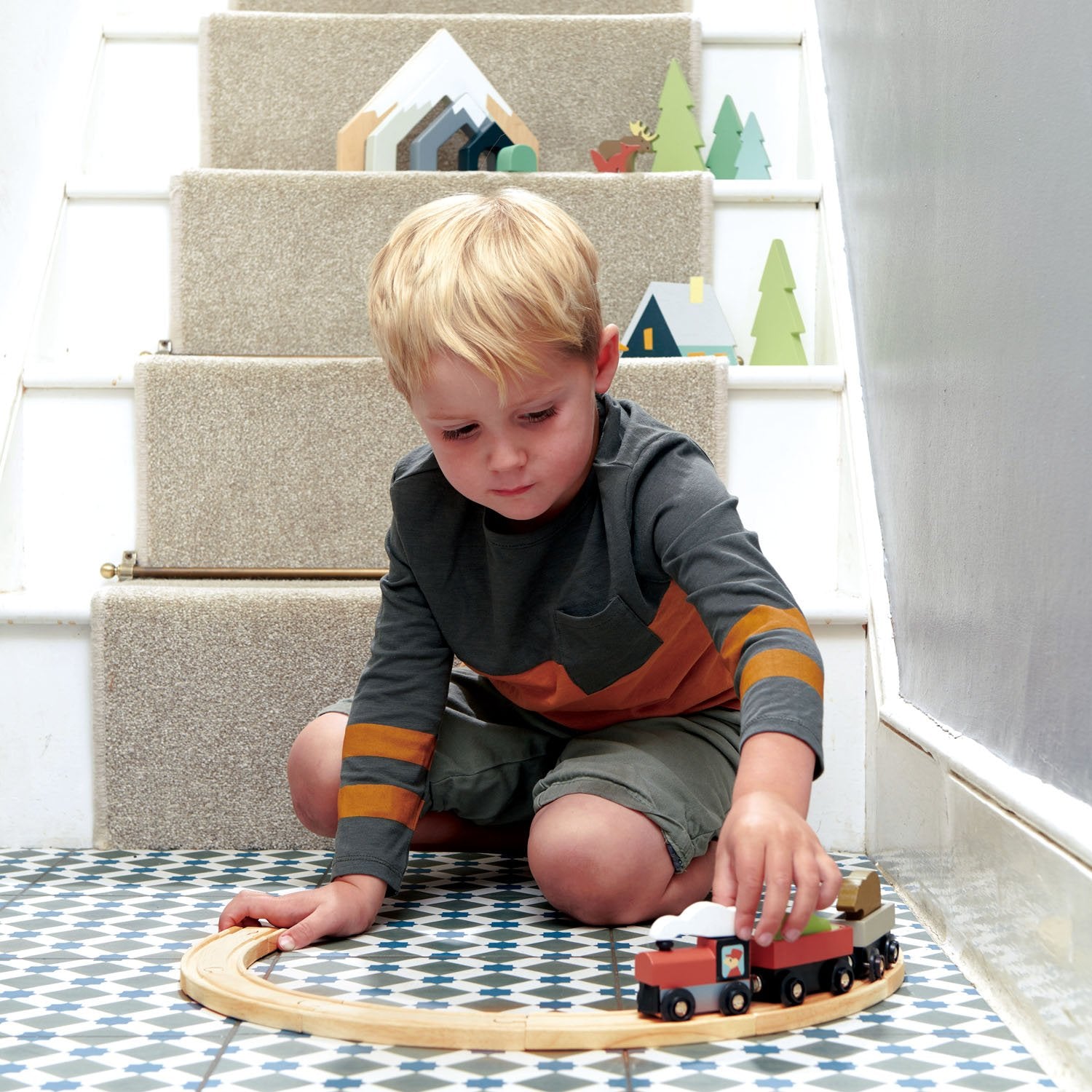 Boy having fun with wooden treetops train set