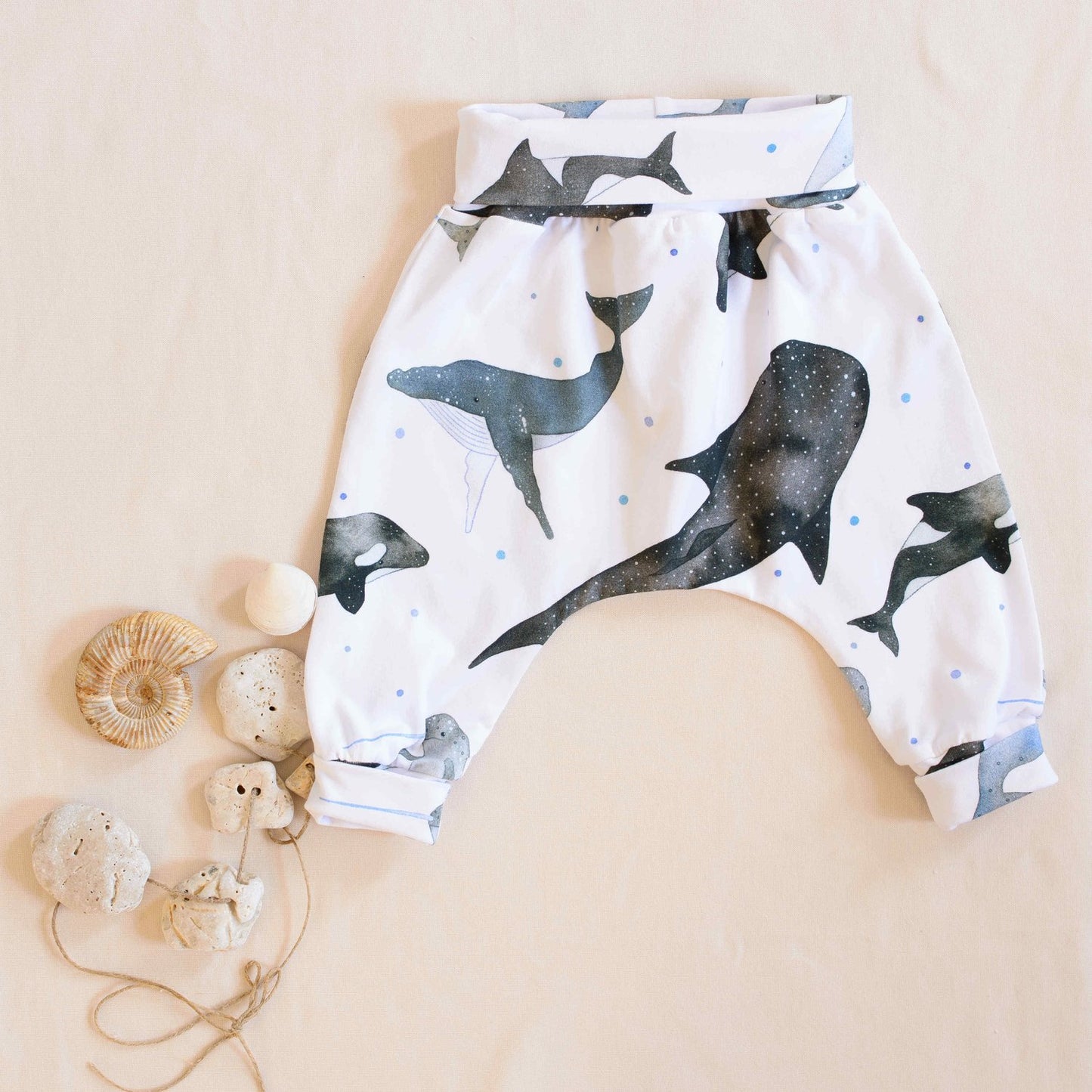 Organic whales trousers folded displayed next to shells and pebbles