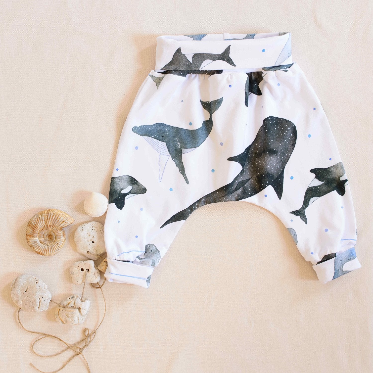Organic whales trousers folded displayed next to shells and pebbles