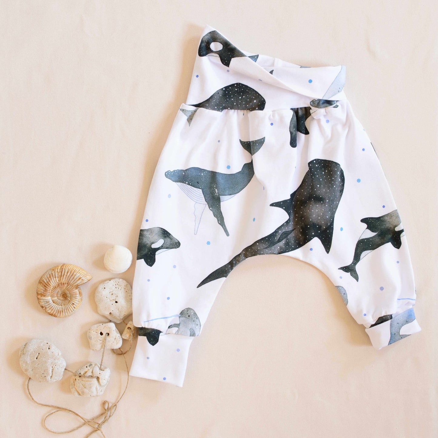 Organic whales trouser half folded displayed next to shells and pebbles