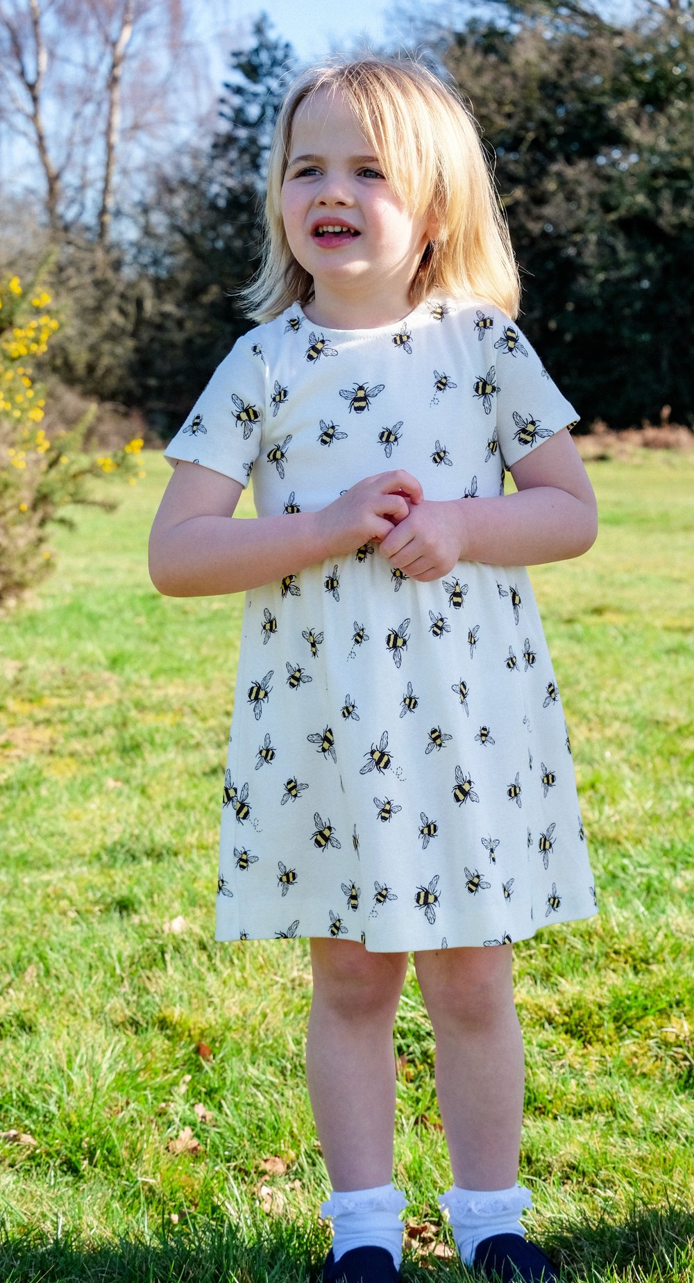 Girl standing in the garden wearing organic white bumblebee dress