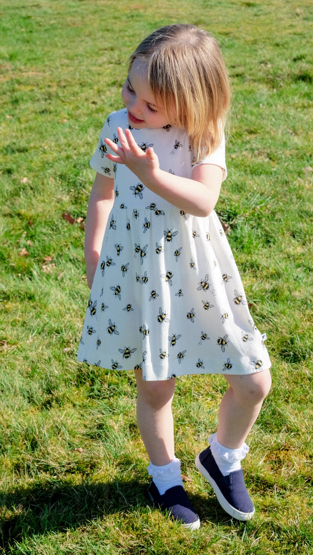 Girl playing in the garden wearing organic white bumblebee dress