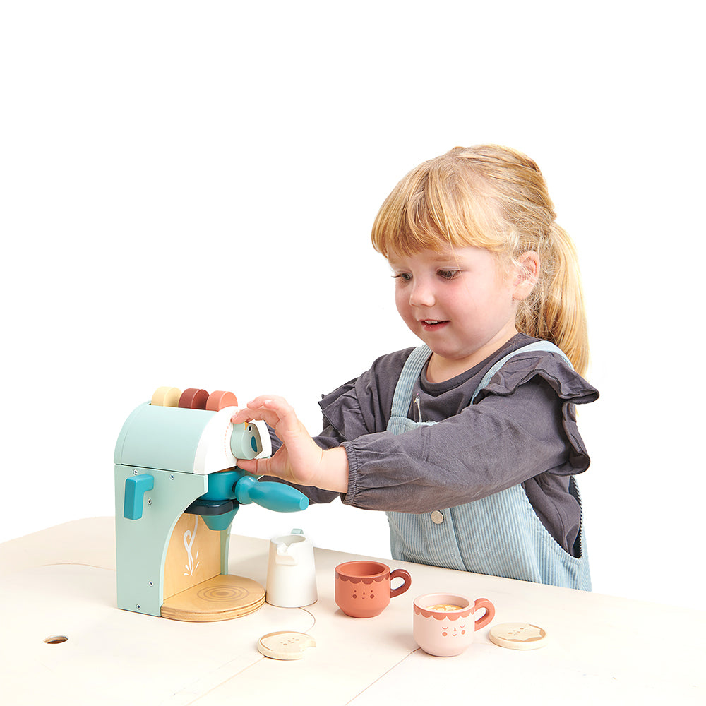 Girl having fun with wooden babbyccino maker set