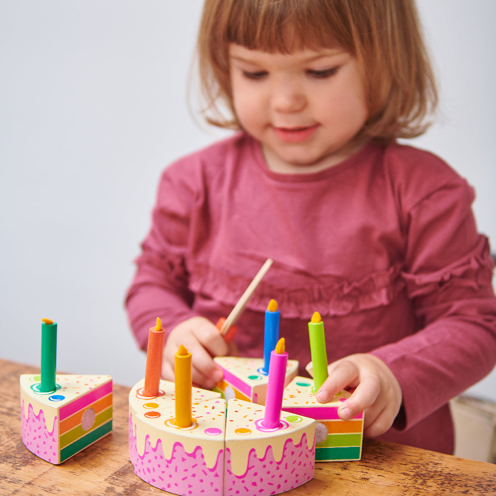 Girl role playing with wooden birthday cake set