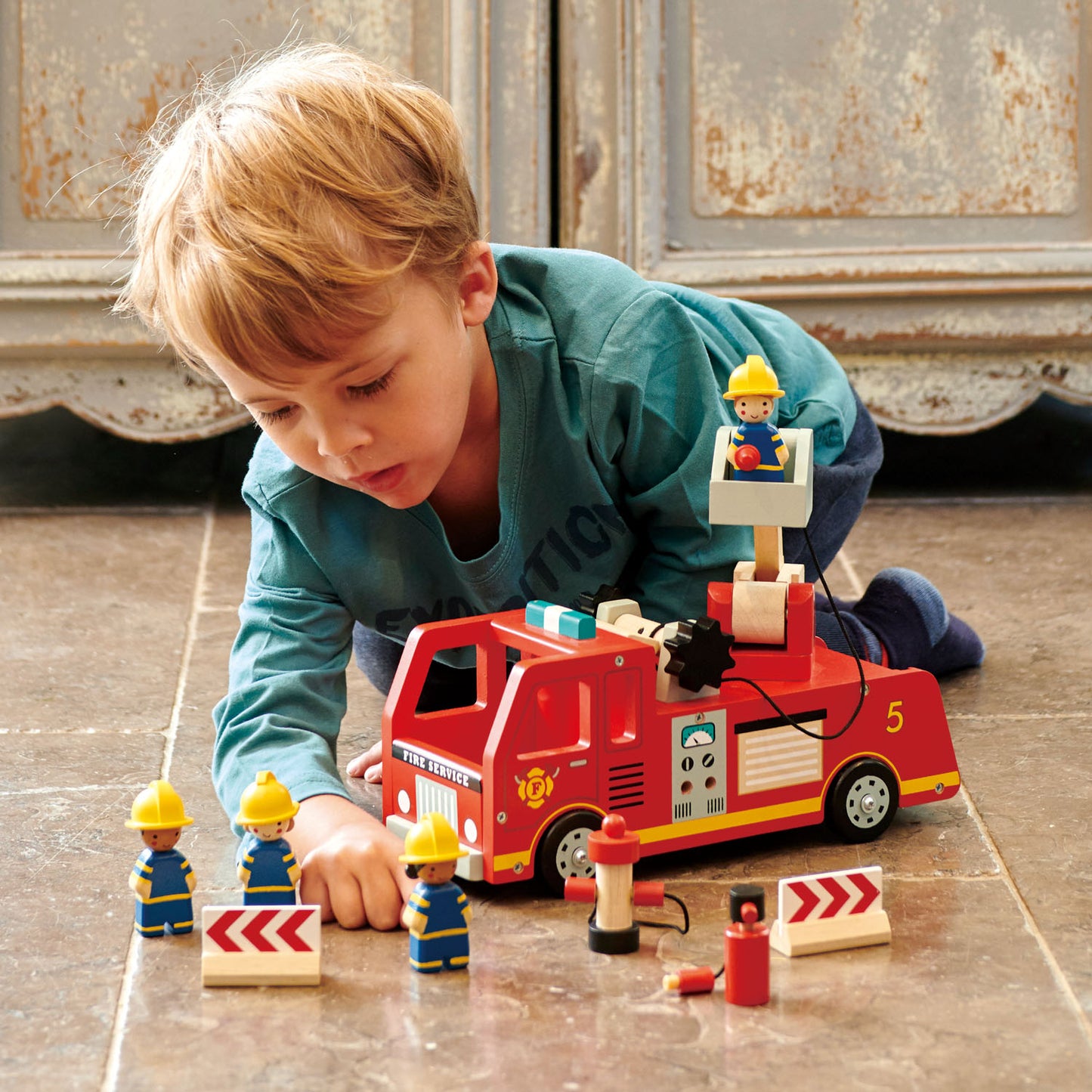 Boy having fun with wooden fire engine set