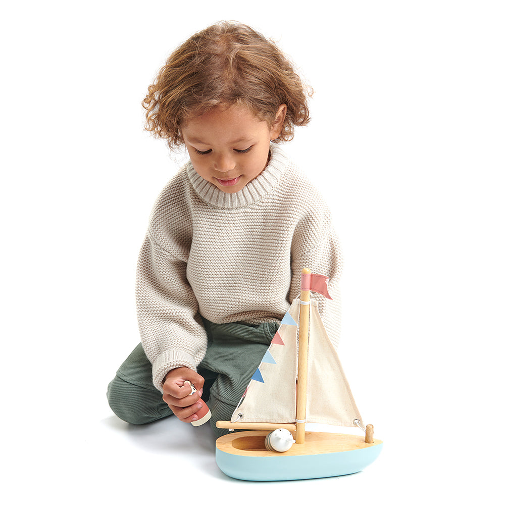 Child playing with wooden sail away boat set