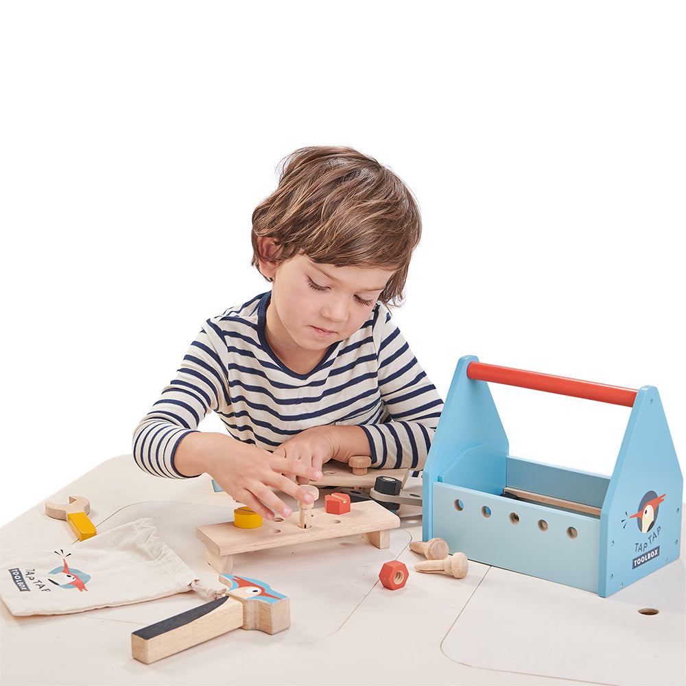 Boy playing with wooden tap tap tool box set